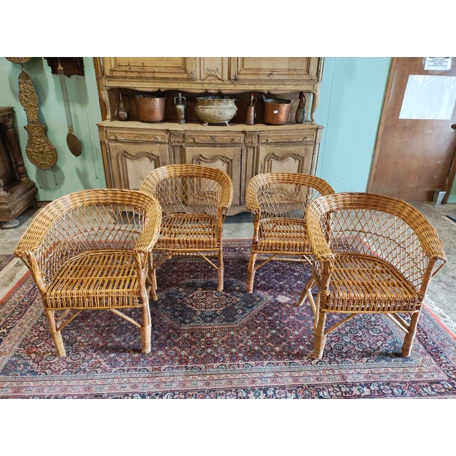 A charming mid-century rattan seating set consisting of four barrel-back lounge chairs and a coordinating round wicker...