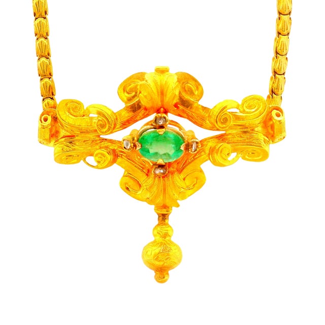 An exquisite necklace featuring a captivating oval-cut emerald as its centerpiece. The emerald displays a vibrant green...