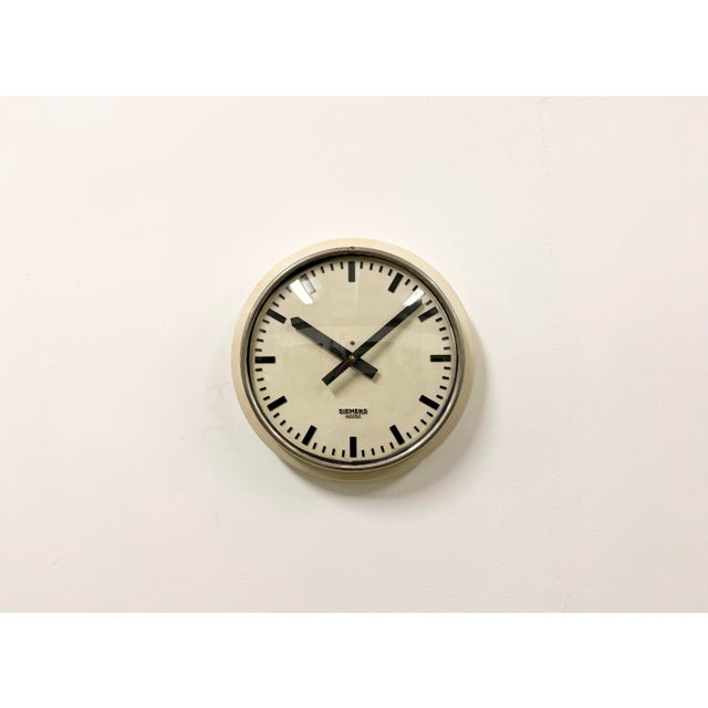 This wall clock was produced by Siemens Austria during the 1960s. It features a beige metal frame, and dial, an aluminum...