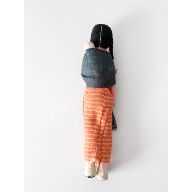 Vintage handmade folk art cloth doll with a hand-painted face, braided yarn hair, a woven striped skirt, and a dark shawl...