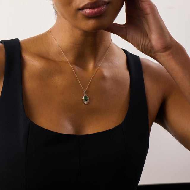This elegant Edwardian pendant necklace centers on a beautifully colored oval green tourmaline weighing approximately 2.20...