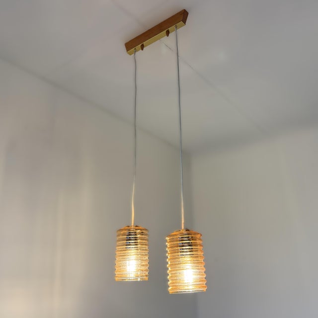 Subtle vintage ceiling lamp consisting of a wooden ceiling plate with two amber pendant lights mounted on it. These ribbed...