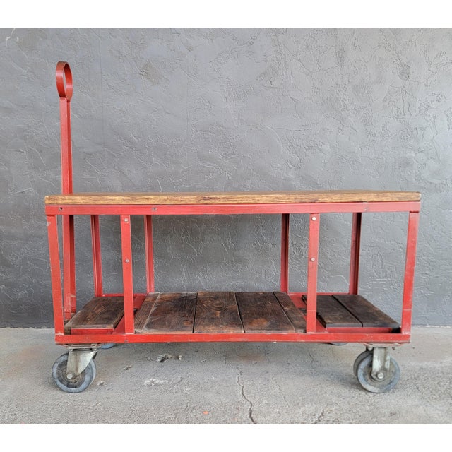 Unusual industrial rolling cart with retractable handle. Red painted steel with solid oak top surface. Wood at base...