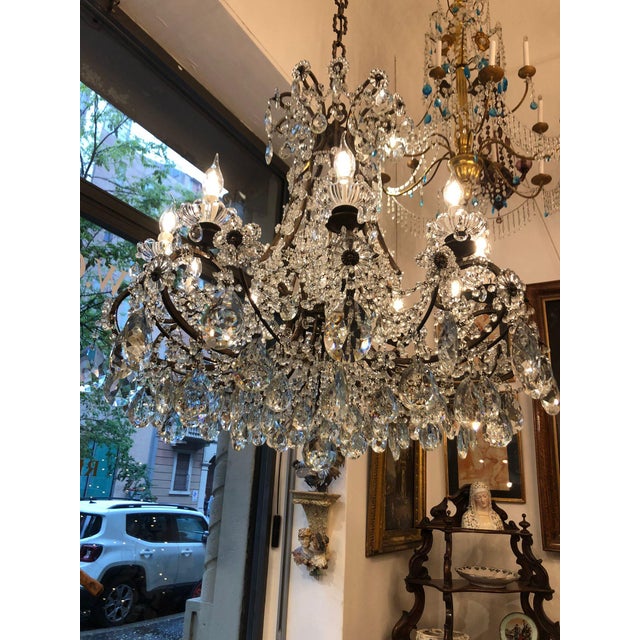 A ten-light crystal dining room chandelier, circa 1950, features a circular, square-section brass frame and ten curved...