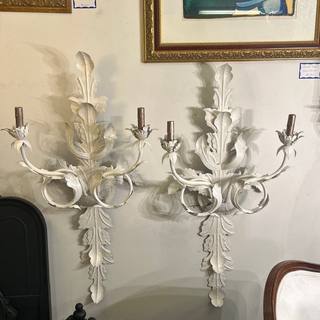 Pair of white painted metal wall sconces featuring a decorative leaf design. Great for ambient lighting with candle-style...