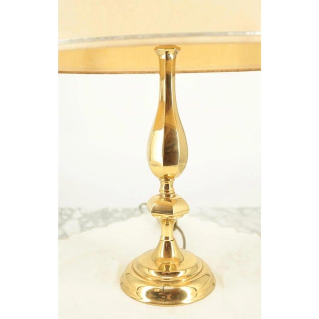 A bright lamp for a chest of drawers or a bedside table made of polished brass with a fabric shade. The lamp is for one...