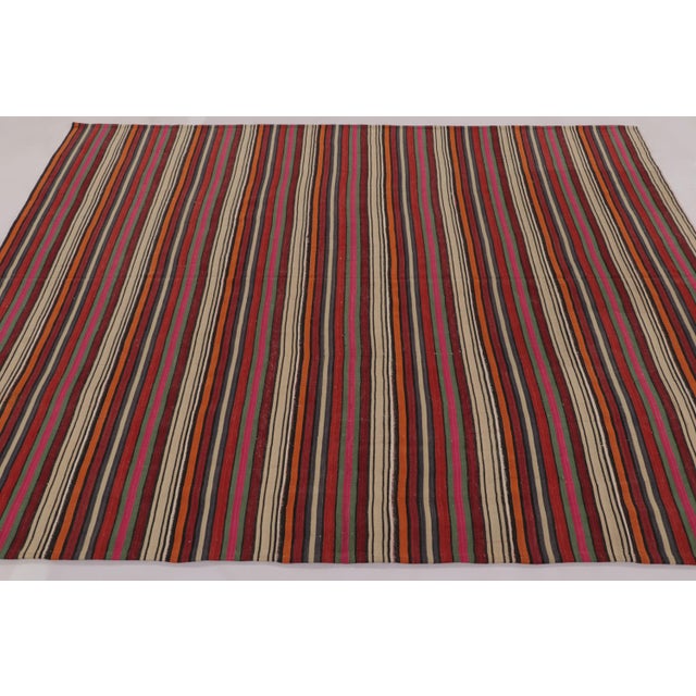 Made with handwoven wool circa 1950-1960, this 8x6 vintage flat-weave Kilim is a particularly spirited and sought-after...