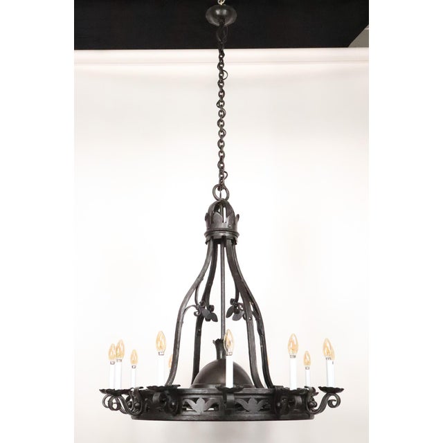 Gothic style chandelier made of hand forged wrought iron. It features an openwork crown finial, a heavy central ring band...