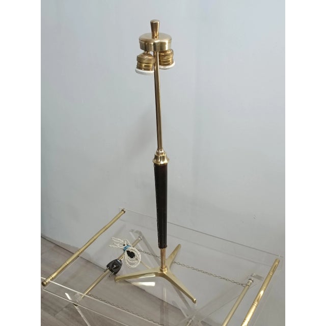 Magnificent table lamp by Jacques Adnet. France, 1950s. Brass frame with tripod base. Partially upholstered in black...