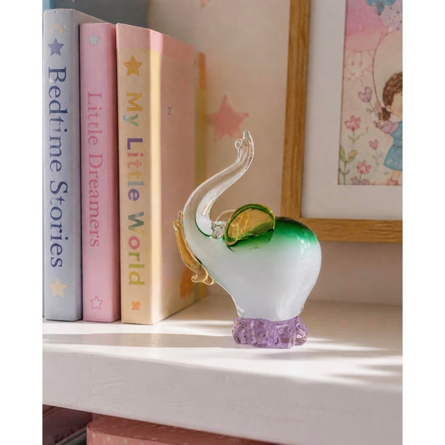 A captivating and joyful piece of decorative art glass, this hand-blown elephant figurine raises its trunk skyward in the...