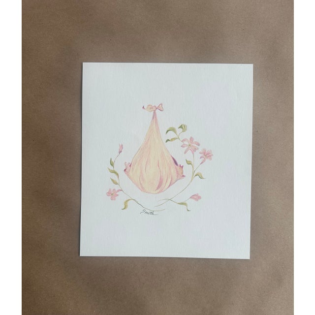 This tender and minimal composition features a softly shaded, ribbon-tied baby bundle surrounded by delicate pink blossoms...