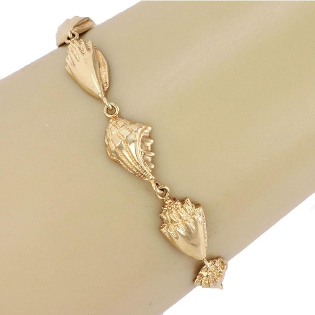 The Eight Conch Seashell 14k Yellow Gold Charm Bracelet is a stylish and elegant piece of jewelry that features a unique...