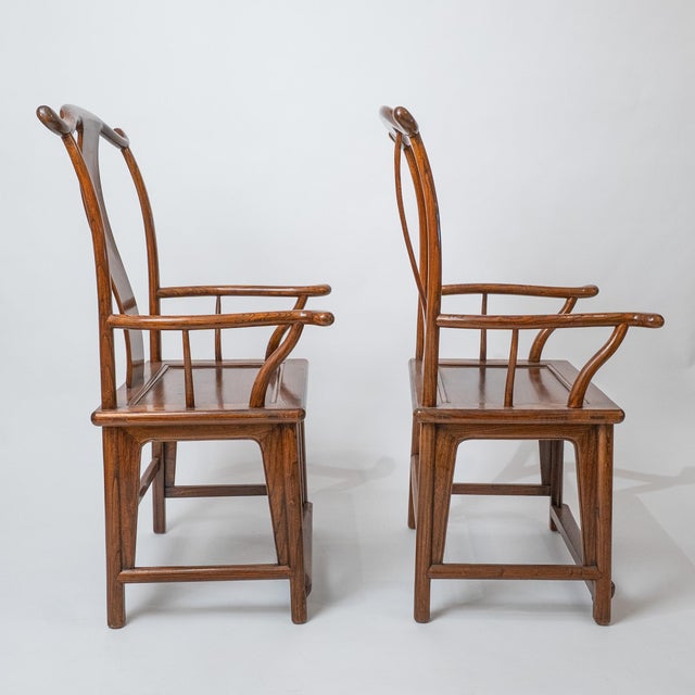Elegant pair of mid-20th century Chinese Ming-style horseshoe armchairs crafted from solid elm. These chairs feature the...