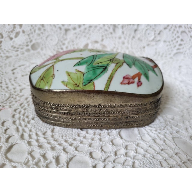 A pink and green floral porcelain and embossed hammered metal box, measuring 6” x 5” x 2 ¼”. This would make a lovely...