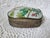 A pink and green floral porcelain and embossed hammered metal box, measuring 6” x 5” x 2 ¼”. This would make a lovely...