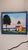 Colorful painting with a scene of the ocean, two residents, hut or house along with a tall tree. Painting signed in the...