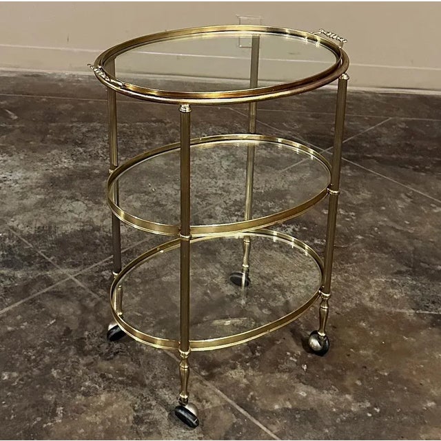Mid-Century Brass & Glass Oval Bar Cart creates a charming way to serve drinks, desserts or treats to your guests and...