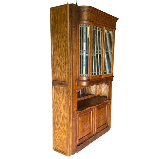 An Art Nouveau oak bar-back cabinet, circa 1910, with leaded beveled glass doors and carved ornament. The tall...