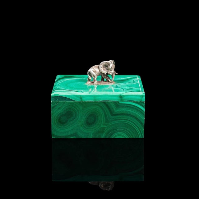 This is a small antique trinket box. An English, malachite and silver decorative box with elephant finial, dating to the...