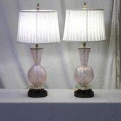 A Murano glass lamp made by Barovier Toso. Glitter swirl glass in a light pink capped with darkened brass accents. The...