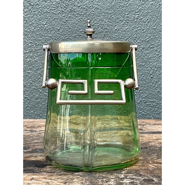 This vintage green glass and metal ice bucket brings mid-century function and sculptural detail to a well-appointed bar or...
