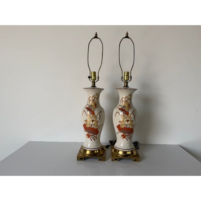 Elegant pair of 1970s vintage table lamps featuring a classic Chinoiserie aesthetic with beautifully detailed lotus floral...