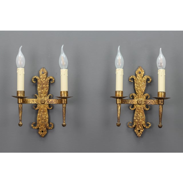 Late 19th-century French gilt wrought iron two-light sconces, set of two. A beautiful pair of Medieval-style sconces,...