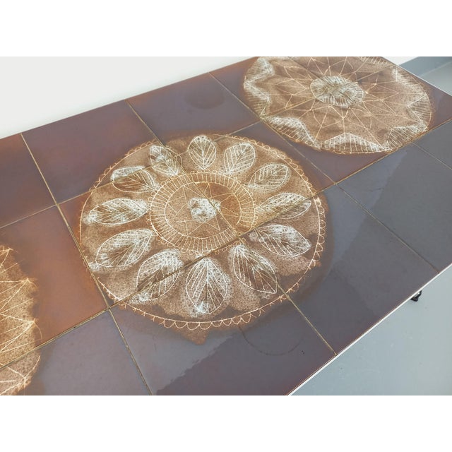 Vintage coffee table from the 70s, ceramic top with “lace” or flower patterns on a brown background and chrome metal base...