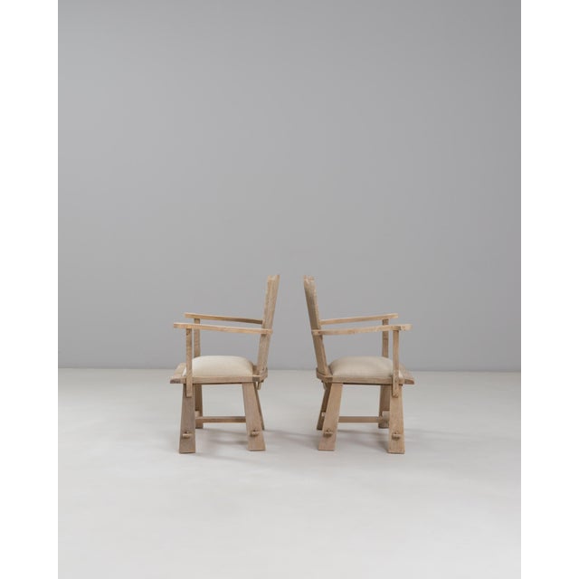 This pair of 1970s French carved oak armchairs brings together rustic charm and artisan detail, showcasing hand-carved...