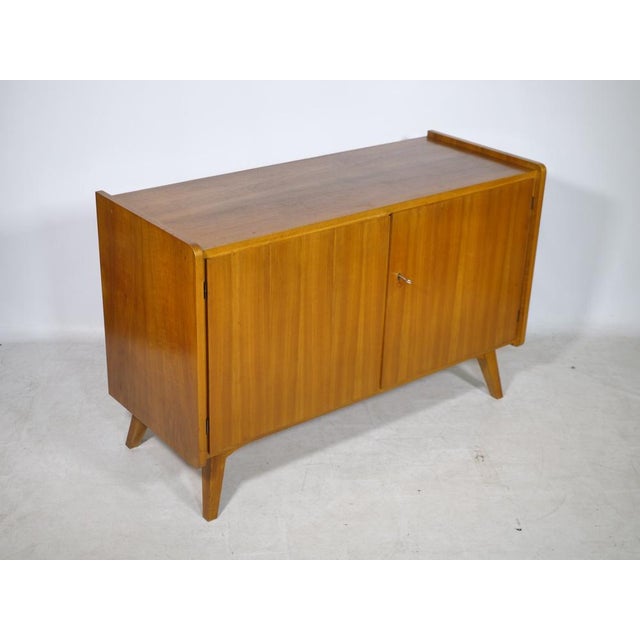 Vintage walnut sideboard from the 1960s. The understated design features rounded sides, angled legs, and two lockable...