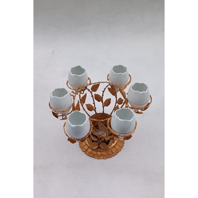 Gilded bronze egg cup with plant motifs, holding six white ceramic eggs. Italian manufacture from the 1960s/1970s, in...