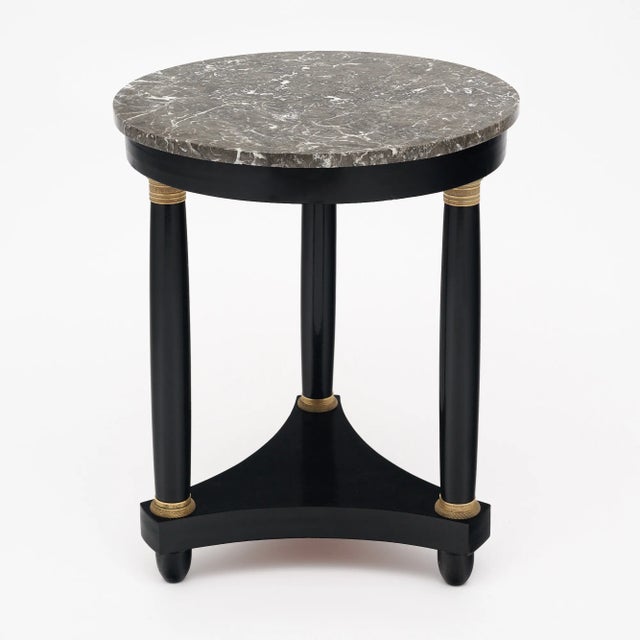 Gueridon side table from France in the Empire style. This piece has three column legs each adorned with brass detailing at...