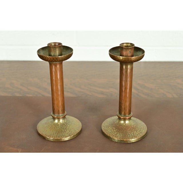 A gorgeous pair of Arts & Crafts period brass finished hand hammered copper candlesticks By Roycroft (signed with...