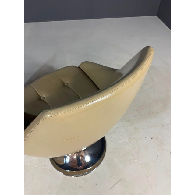 A stylish pair of vintage swivel chairs from the 1970s, featuring sculptural beige upholstered seats and polished chrome...