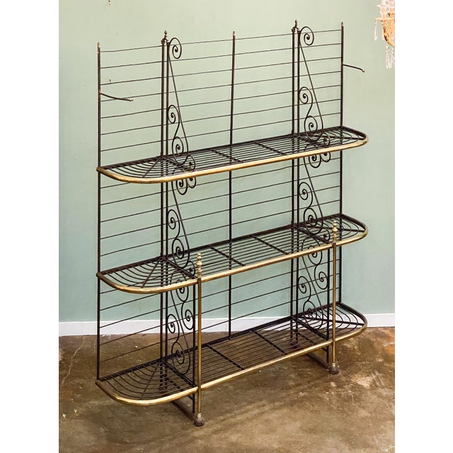 A large French baker's rack or boulangerie display stand of wrought iron with decorative brass trim and finials, featuring...