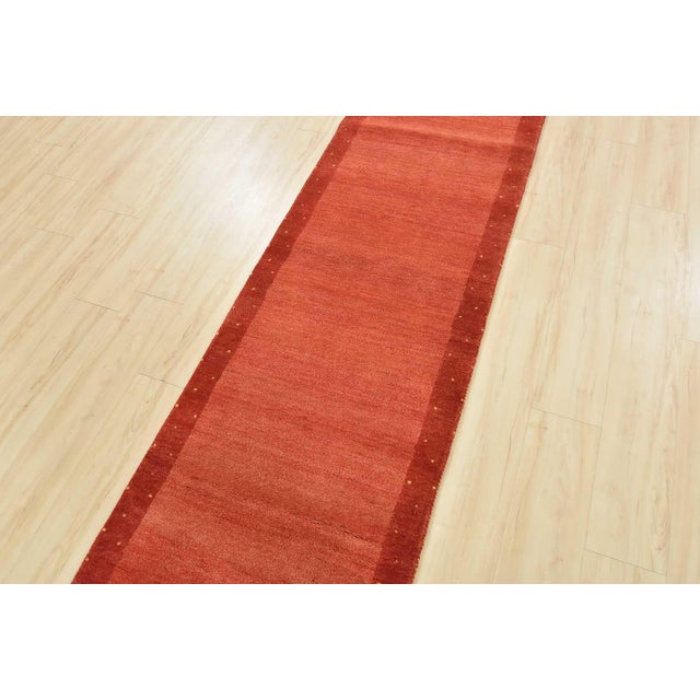 A contemporary Gabbeh runner hand-knotted with an all-wool pile on a cotton foundation. This oriental rug features a solid...