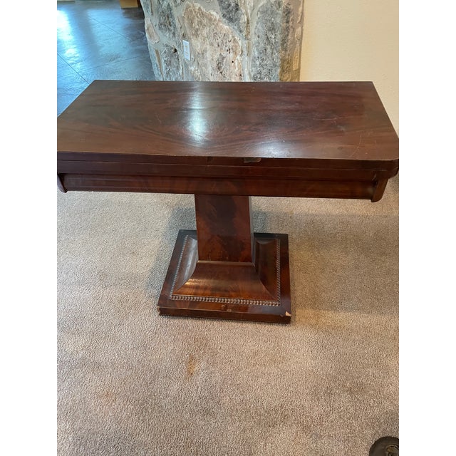 American Empire Style Console or Game Table. Mahogany with square top that folds in half on a pedestal base. No storage...