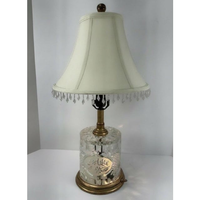 An elegant vintage table lamp featuring a substantial cylindrical cut-crystal body mounted on a warm brass-tone base. The...