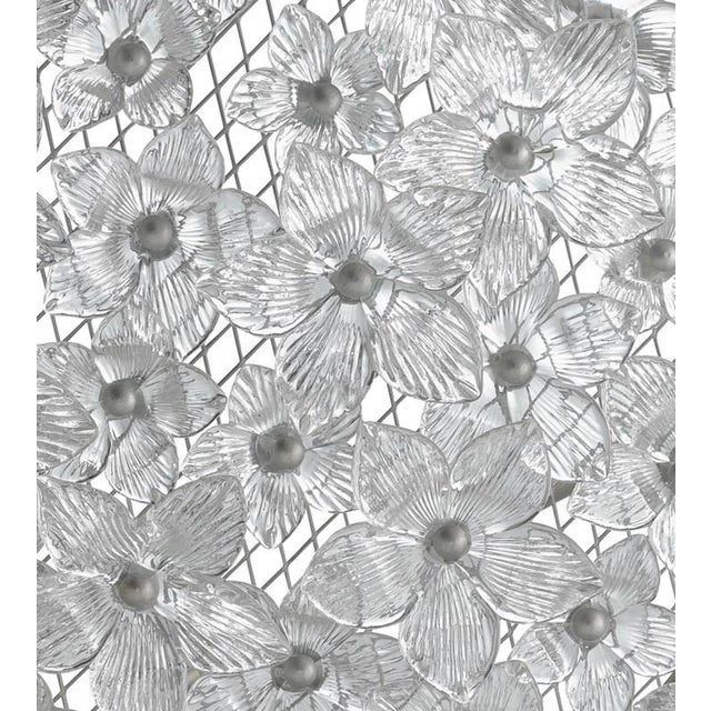 The Belinda Chandelier with its dome shape completely covered in hundreds of gleaming glass flowers is a large-scale piece...