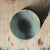 The artwork features a large, rounded form that dominates the canvas, rendered in a cool palette that contrasts with the...