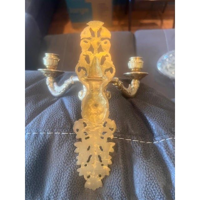 These elegant wall sconces feature an ornate, neoclassical-inspired design with decorative scrolling and metallic finish....