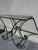 An elegant vintage wrought iron console table with a light, architectural silhouette composed of graphic curves and a...