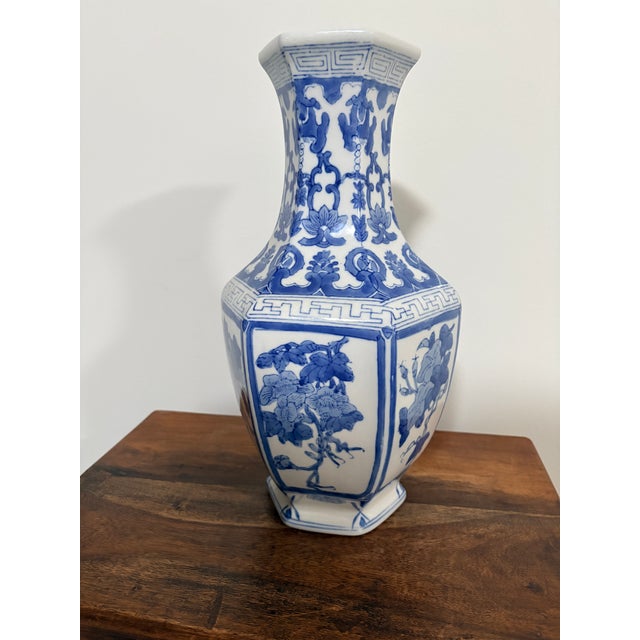 “Vintage blue‑and‑white ceramic vase with a hexagonal form and hand‑painted floral motifs. Heavier ceramic body with a...