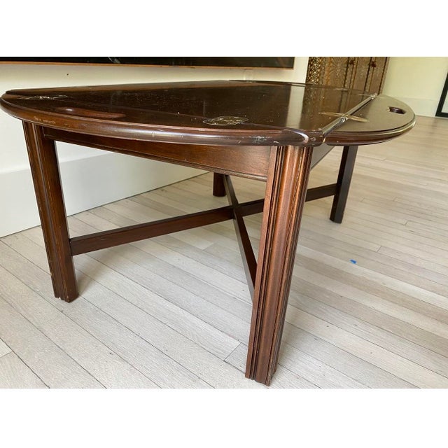 Vintage 1970s campaign Butler’s coffee table. Dark finished wood with brass hardware. Rectangular top with curved drop...