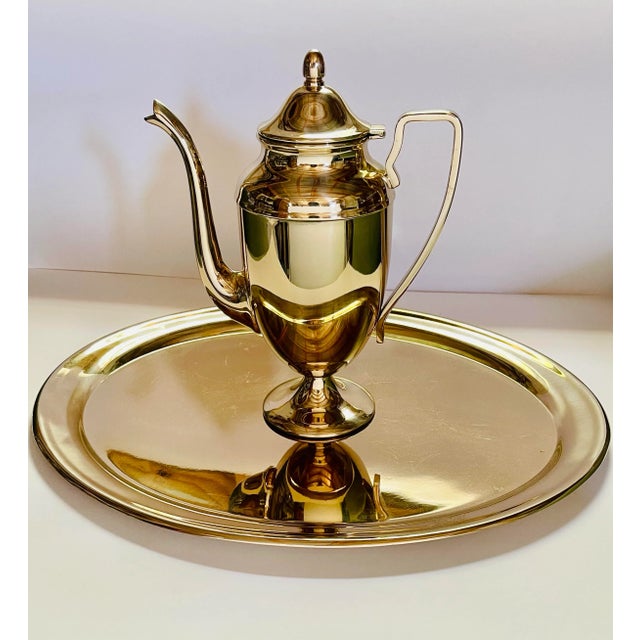 A gold tinted bronze alloy coffee pot in the Hollywood Regency style. The pot has a classical urn shaped body, a thin...