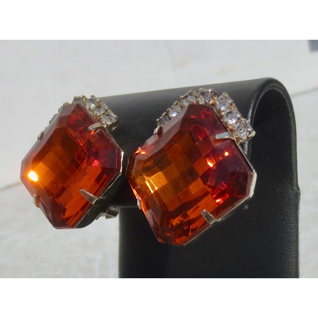Faux Maderia Topaz faceted crystal in gold-plated metal clip-ons. Rhinestone-edged center stone. The measurements are...