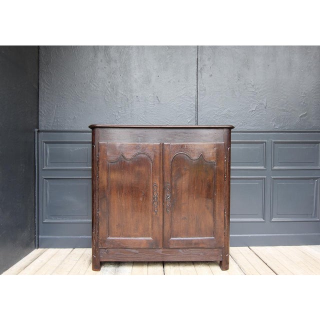 A French provincial Louis XV sideboard from the 18th century. Made of solid oak wood with waxed surface. Two-door side-...