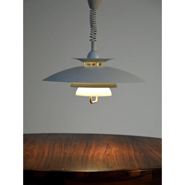 "Lisa" pendant lamp by Eklunds in matte white painted metal, multi-disc shielding structure with brass details. "Lisa"...