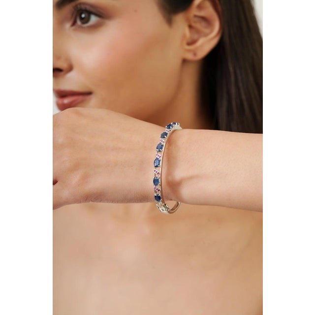 This elegant vintage bangle bracelet is crafted in solid 925 sterling silver and beautifully adorned with natural blue...