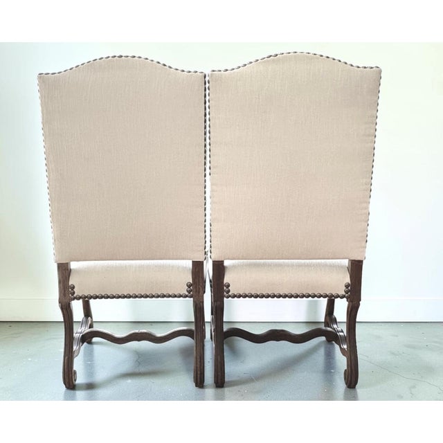 A handsome pair of French fruitwood armchairs featuring gracefully scrolled arms, shaped stretchers, and elegantly carved...